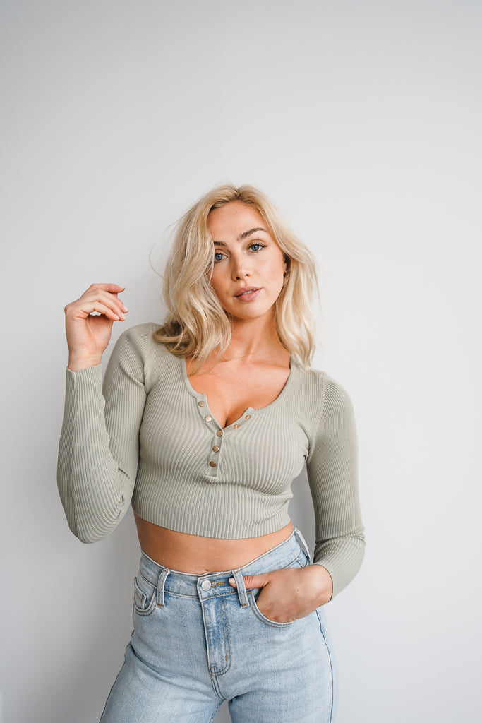 A ribbed long sleeve crop top featuring deep v-neck and snap button closure.