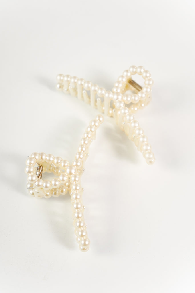 A high-polish hair clip featuring a claw design and pearl décor.