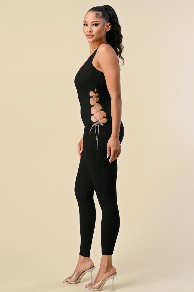 A slim-fit ribbed jumpsuit featuring sides cuts with rhinestone lace.