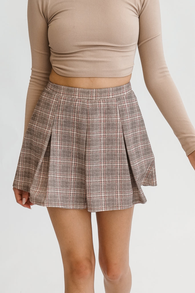 A brown mini pleated plaid skirt featuring an elasticized waist.