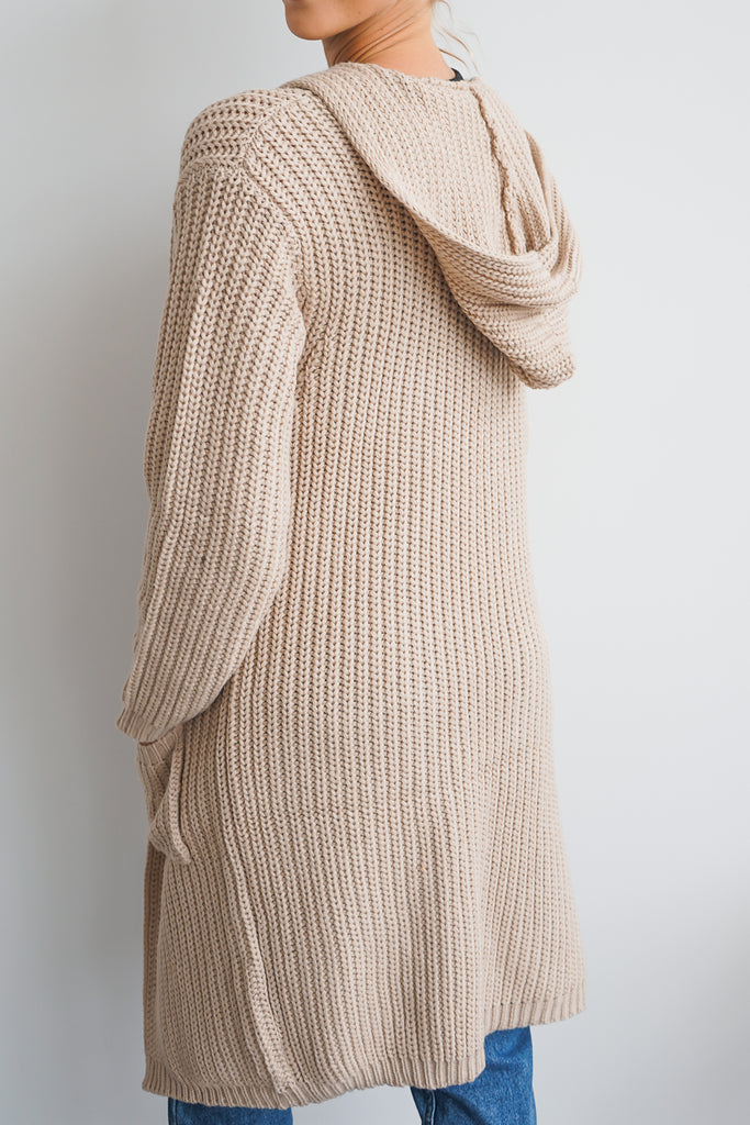 An oversized long cardigan featuring a hood, pockets, and long sleeves