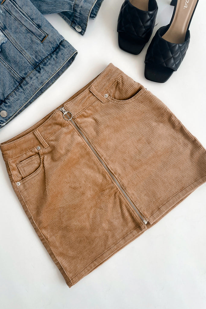 A mini corduroy skirt featuring a front zipper opening, and size pockets.