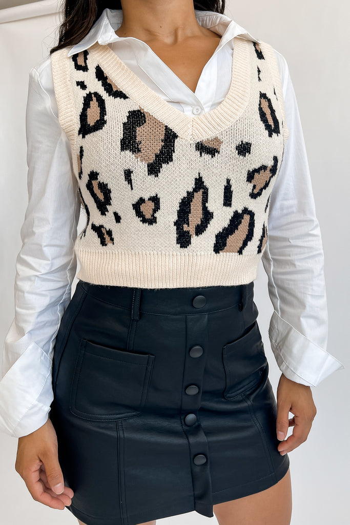 A woven knit sweater vest crop top featuring an allover leopard print, a v-neck and ribbed hem.