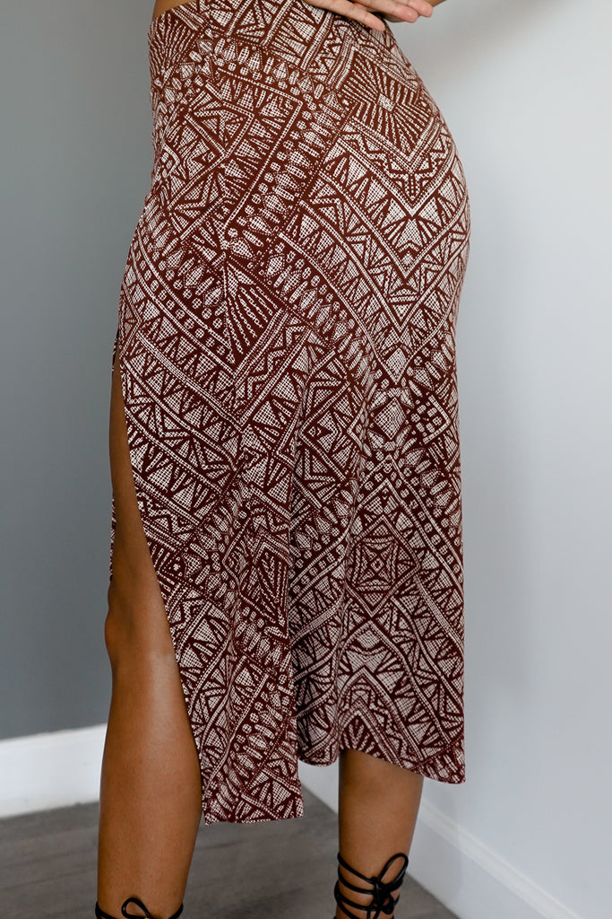 A midi skirt featuring a straight silhouette, knee length, leg slit, and a elastic waist.