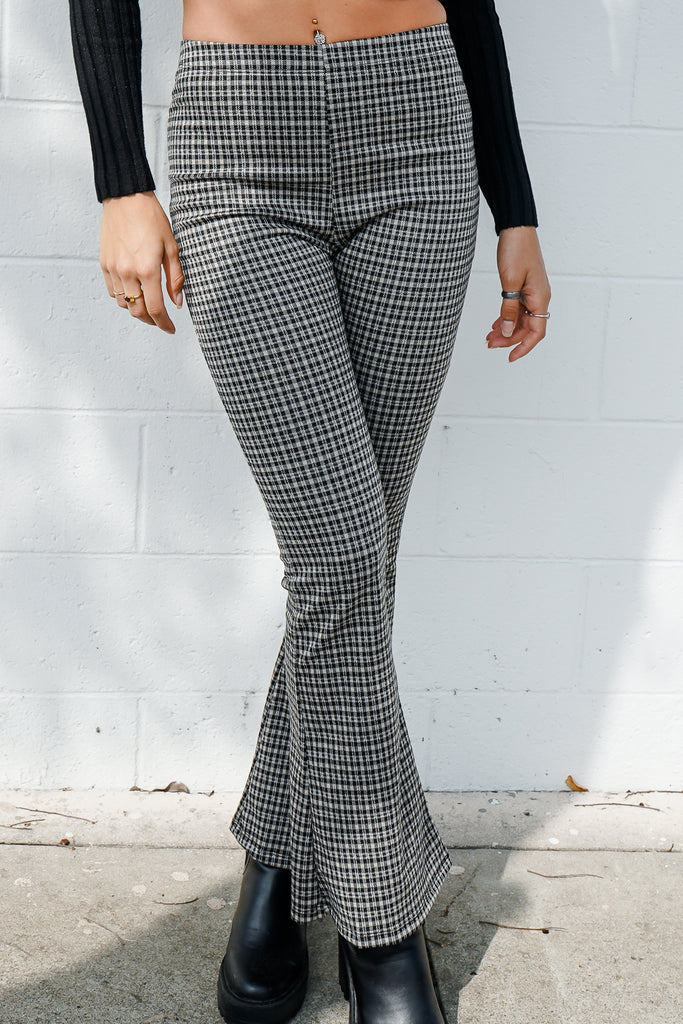 A pair of woven pants featuring an allover plaid pattern, high-rise waist, and flare leg.