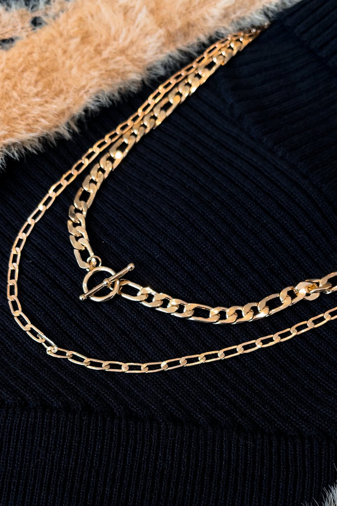 A high-polish layered necklace featuring a Figaro, chunky curb, with toggle and lobster-clasp closures.