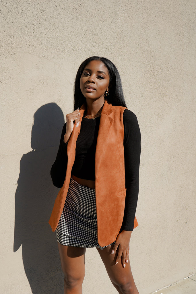 A suede open vest featuring a longline silhouette, notched lapels, and sleeveless.  