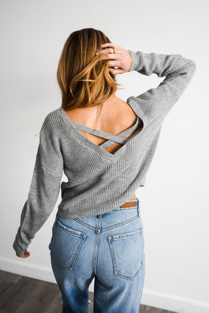 A knit sweater featuring a long sleeves and an open back.