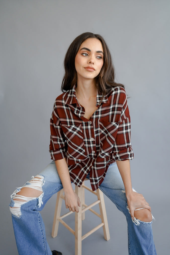 A button-up plaid crop top featuring a collar, and an adjustable self-tie on the bottom.