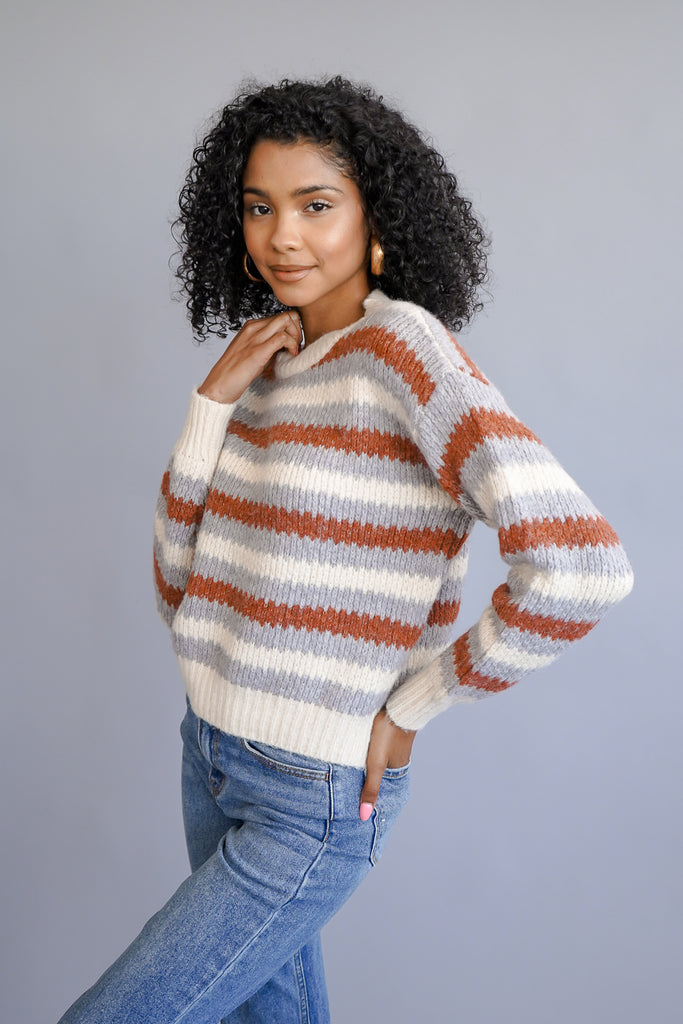 A thick knit sweater featuring a striped pattern and long sleeves.