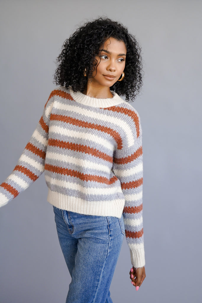 A thick knit sweater featuring a striped pattern and long sleeves.