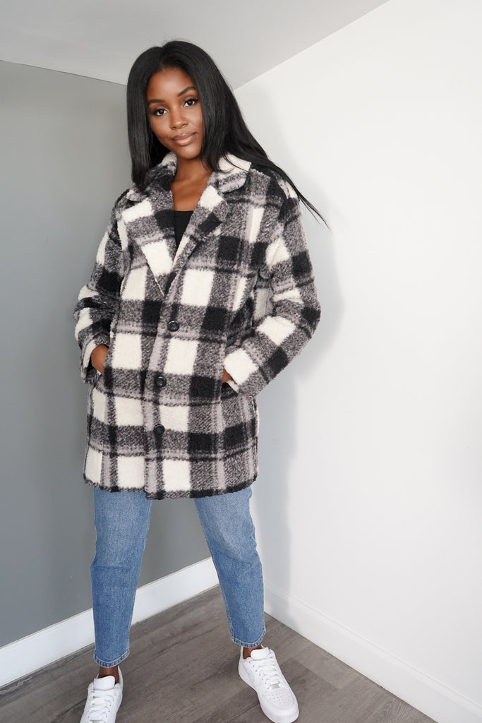 A faux shearling coat featuring an allover plaid pattern, wide notched lapels, foldover collar, button-front closures, dropped long sleeves, woven lining, and longline length.