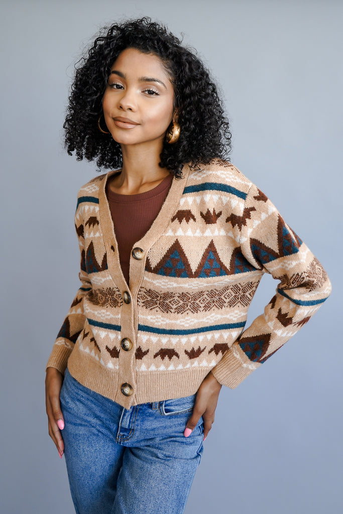 A cropped knit cardigan featuring a V-neckline, buttons in the front, and long sleeves.