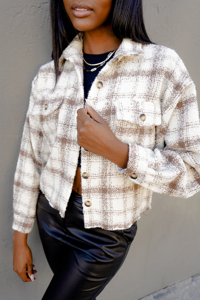 A fuzzy plaid crop jacket featuring long sleeves, button-up in front, a collar, and pockets.