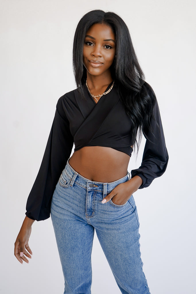 A satin crop top featuring a plunging V-neckline, long sleeves with shirred accents, and front self-tie closure.