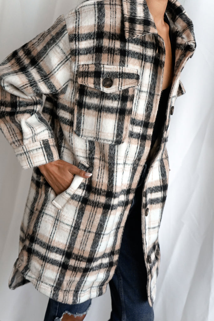 An oversized button-up plaid coat featuring a collar, long sleeves and pockets.