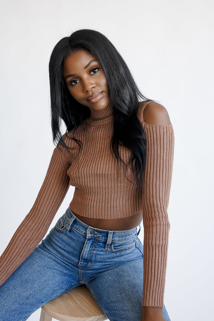 A ribbed knit sweater featuring a turtle neck, open-shoulder design, and long sleeves.