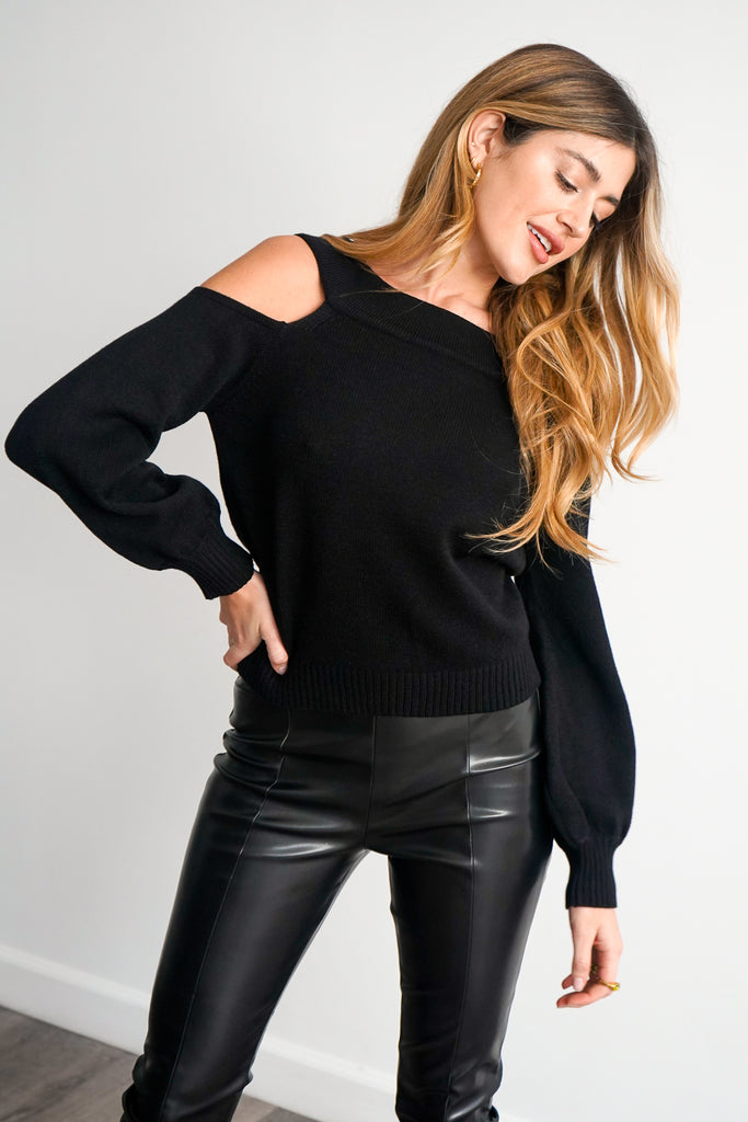 A ribbed knit sweater featuring a boat neck, dropped shoulders, and side cutouts on the long dolman sleeves.