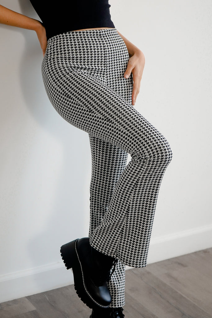 A pair of woven pants featuring an allover hounds tooth pattern, high-rise waist, and flare leg.
