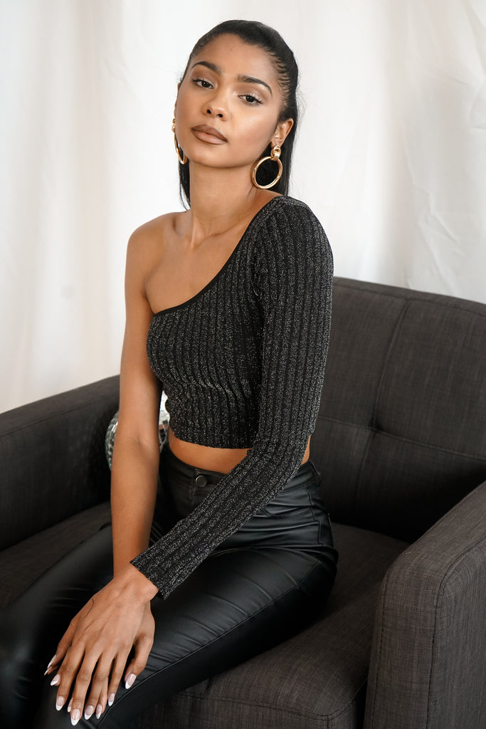 A black one-shoulder long sleeve top featuring an allover sparkle, one-shoulder neckline, and a cropped hem.
