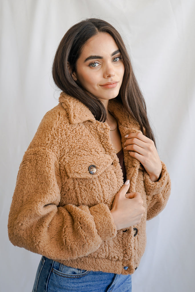A plush and fuzzy faux fur jacket featuring a collar, button-up front, and long sleeves.