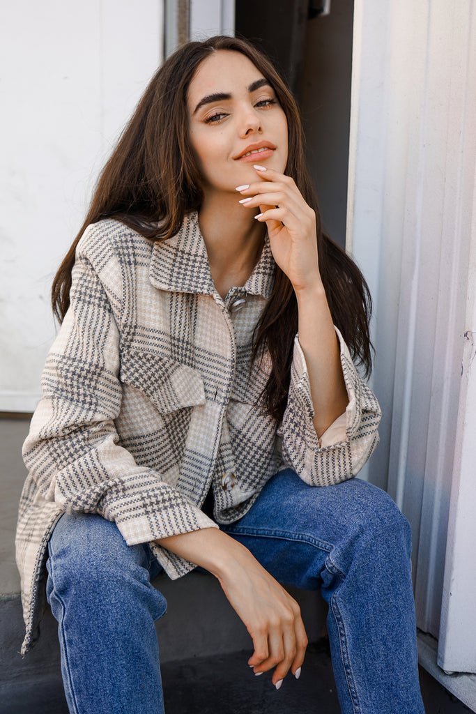 A button-up plaid coat featuring a collar, long sleeves and pockets.